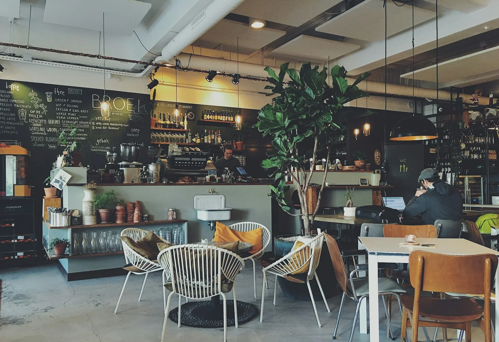 A tranquil sunlit courtyard garden café with wooden tables and plants